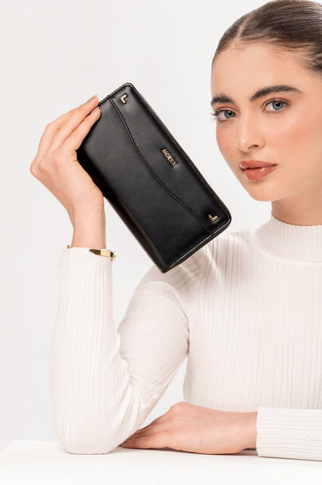 Mujer con suéter blanco sosteniendo cartera negra de cuero Möxx con cierre dorado