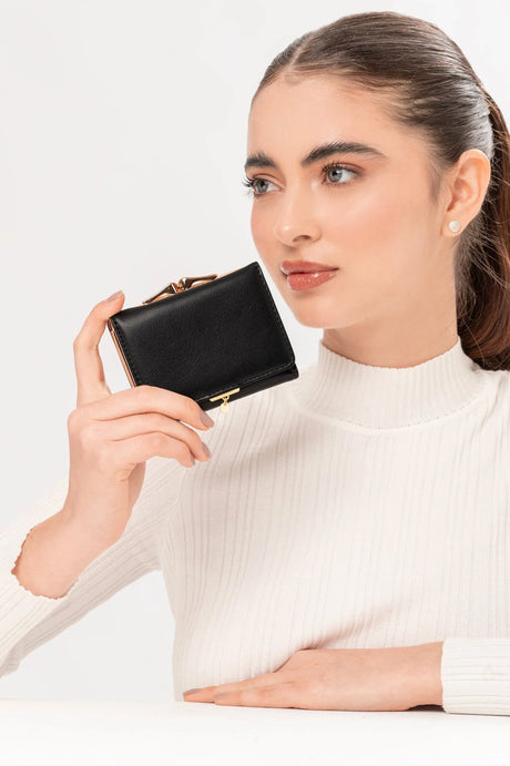 Mujer con suéter blanco sosteniendo billetera negra de cuero con detalles dorados