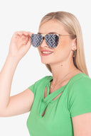 Mujer rubia con camiseta verde y gafas de sol espejo con diseño geométrico negro y gris