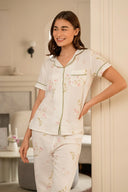 Mujer sonriendo con pijama blanco floral de manga corta en interior elegante moderno