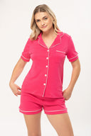 Mujer con pijama rosa de camiseta de botones y shorts, fondo blanco, moda femenina cómoda