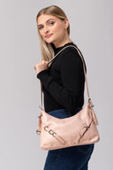 Mujer rubia con suéter negro y jeans exhibiendo bolso rosa beige con correas y hebillas