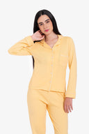 Mujer con pijama amarillo pastel de manga larga y pantalón, fondo blanco