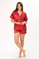 Mujer sonriente con pijama corto rojo con estampado de hojas en fondo blanco