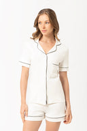 Mujer con pijama blanco de manga corta y shorts con ribetes negros en fondo blanco