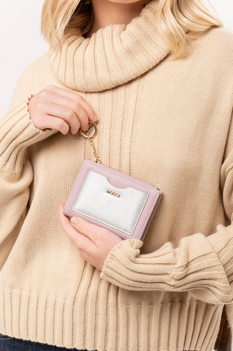 Persona con suéter beige sostiene billetera rosa claro con monedero plateado y llavero dorado MOIXX